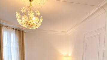 Une chambre d’hôtel avec un lit, un lustre, une table de chevet et une porte.