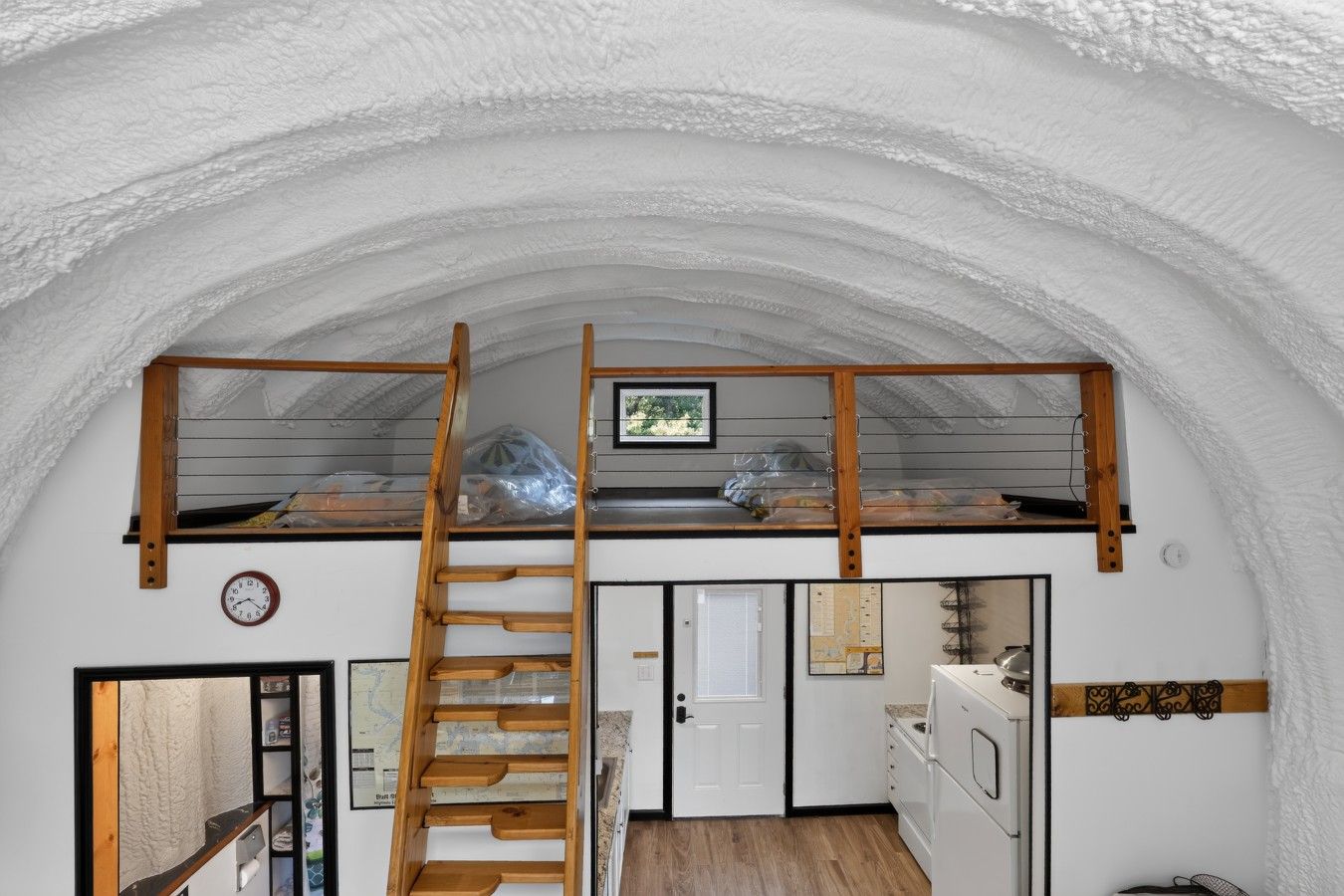 Une cuisine compacte avec un escalier en bois menant à une chambre à coucher située en mezzanine.