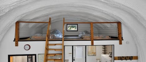 Cozinha compacta com escada de madeira que dá acesso a um quarto no mezanino.