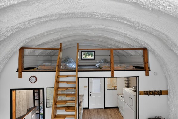 A compact kitchen with a wooden staircase leading to a loft bedroom.