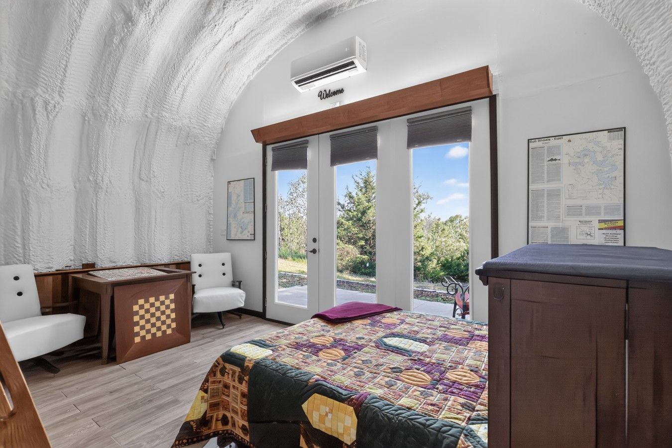A room with a bed, a desk, a chair, and a view of the outdoors.