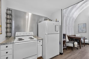A compact kitchen with a stove, refrigerator, and a dining area with a table and chairs.