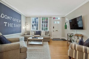 A living room with a sofa, armchairs, a coffee table, a TV, and a wall with motivational text. - Annapolis Charmer - Perfect Location (Annapolis)
