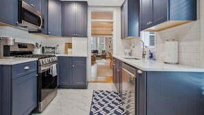 Una cocina moderna con armarios oscuros, horno integrado, microondas y cocina de acero inoxidable.