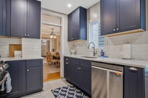 Una cocina moderna con armarios oscuros, un lavavajillas de acero inoxidable y una encimera blanca.