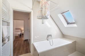 Une salle de bain moderne avec une baignoire, une douche et une fenêtre.
