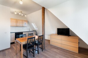 Une cuisine compacte avec un coin repas, un téléviseur intégré et une chambre en mezzanine avec un plafond en pente.