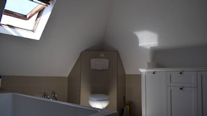 A bathroom with a bathtub, toilet, and a cabinet. - Holiday Home Neuhausen – Attic Apartment / 2 Bedrooms / Wi-Fi (Neuhausen)