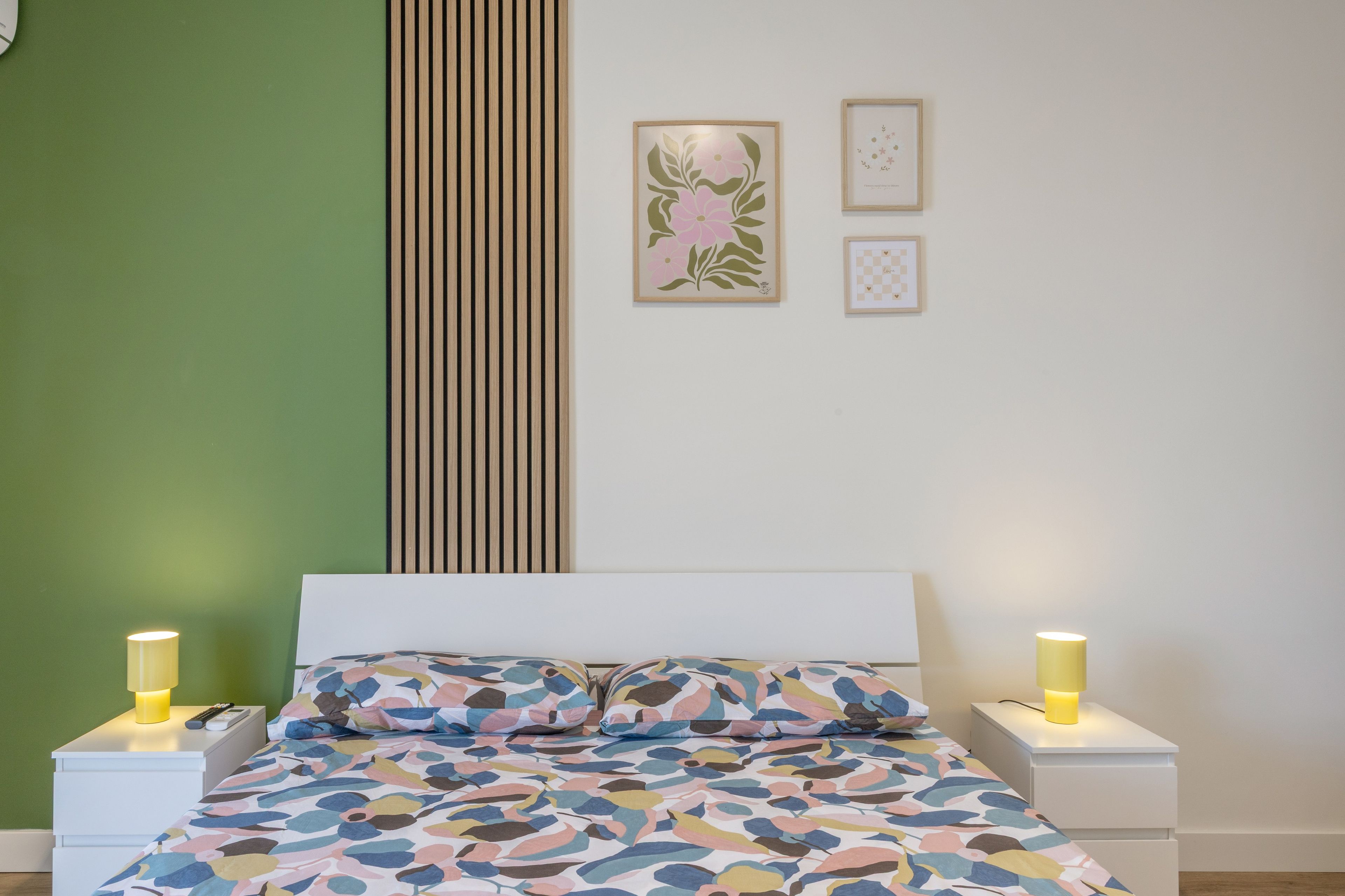 Une chambre à coucher comprenant un lit, deux tables de chevet, une commode et des œuvres d’art accrochées au mur.