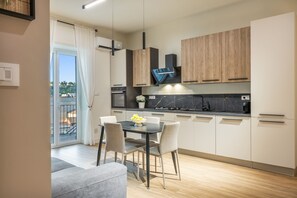 Eine moderne Küche mit Essbereich, ausgestattet mit einem Backofen, einer Kaffeemaschine und einem großen Fenster.