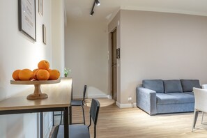 A modern living room with a sofa, a dining table with oranges, and a chair. - Salamon House - Room 003 (Catania)