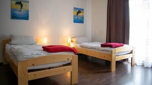 A room with two wooden beds, each with a pillow and a blanket. There are two wall-mounted lamps on either side of the beds. - Neuhausen Holiday Home – Ground Floor Apartment / Wi-Fi / 1 Bedroom (Neuhausen)