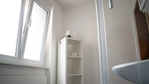 A bathroom with a window, a white shelf, and a white sink. - Neuhausen Holiday Home – Ground Floor Apartment / Wi-Fi / 1 Bedroom (Neuhausen)