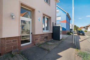 Un immeuble dont le rez-de-chaussée est occupé par un local commercial, avec une entrée bien visible et une voiture garée devant.