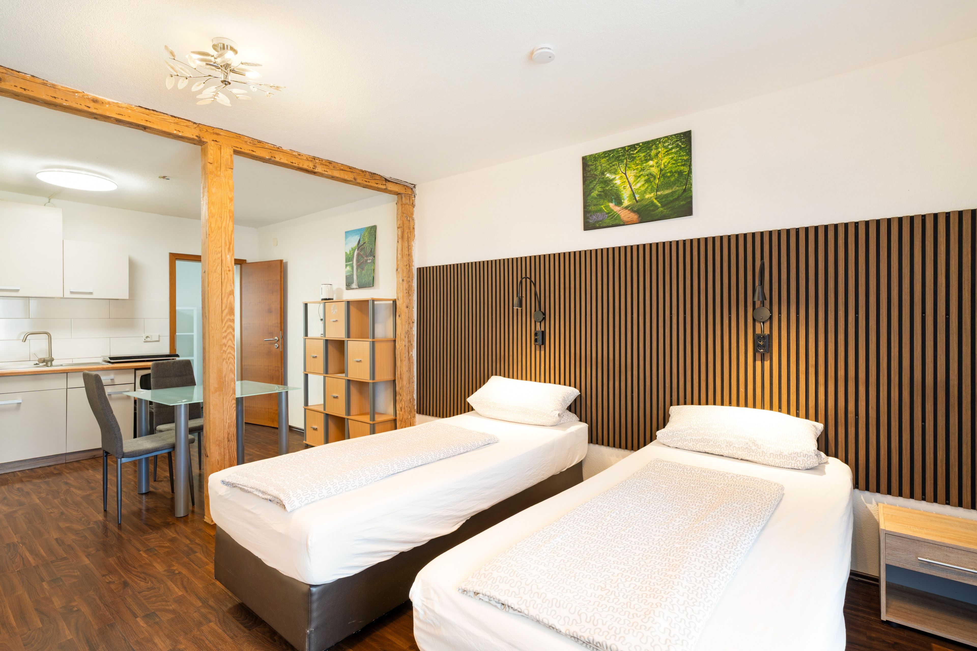 Ein Hotelzimmer mit zwei Betten, einem Schreibtisch, einem Stuhl und einer Wandpaneele aus Holz.