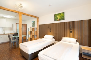 Une chambre d’hôtel avec deux lits, un bureau, une chaise et un mur recouvert de panneaux de bois.