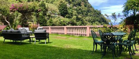 A garden with a table and chairs, a sofa, and a decorative fence.