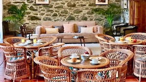 Ein gemütlicher Lounge-Bereich mit Korbmöbeln, einer Steinwand und einer Couch.