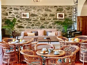 A cozy lounge area with wicker furniture, a stone wall, and a sofa. - Vrbo Property (Santana)