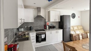 Una cucina moderna con mobili bianchi, forno integrato e zona pranzo con tavolo e sedie in legno.