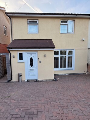 A two-story residential building with a beige exterior, a brown roof, and a white door with the number 23. - Roys House (Oxford)