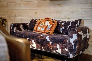 Ein Sofa mit Kuhfellmuster und eine Lederhandtasche mit Reiseaufnähern.
