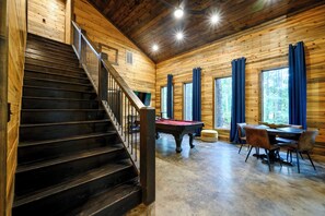 A wooden interior with a staircase, a pool table, and a dining area. - 4 King Suites | Hot Tub & Game Room (Broken Bow)