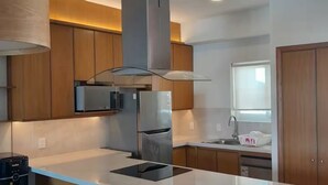 A modern kitchen with wooden cabinets, stainless steel appliances, and a central island. - Cozy 2BD ocean-front condo with tennis courts (Las Jarretaderas)