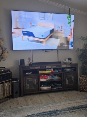 A television displaying a bedroom setup with a Nectar mattress, a wooden headboard, and a bedside table.