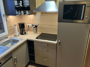 A compact kitchen with a stainless steel refrigerator, a built-in stove, a coffee maker, and a sink. - Cabin in Annaberg With Swimming Pool (Annaberg-Lungoetz)
