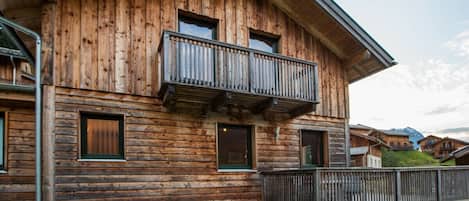 A wooden chalet with a balcony, a covered porch, and a view of the surrounding landscape.