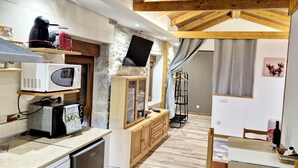 A compact kitchen with modern appliances, a wooden ceiling, and a view of a dining area. - Rural House 'Paraje Do Cura' with Private Terrace and Wi-Fi (Arbo)