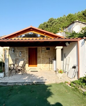 Un bâtiment en pierre avec une porte en bois, un porche couvert et une antenne parabolique.