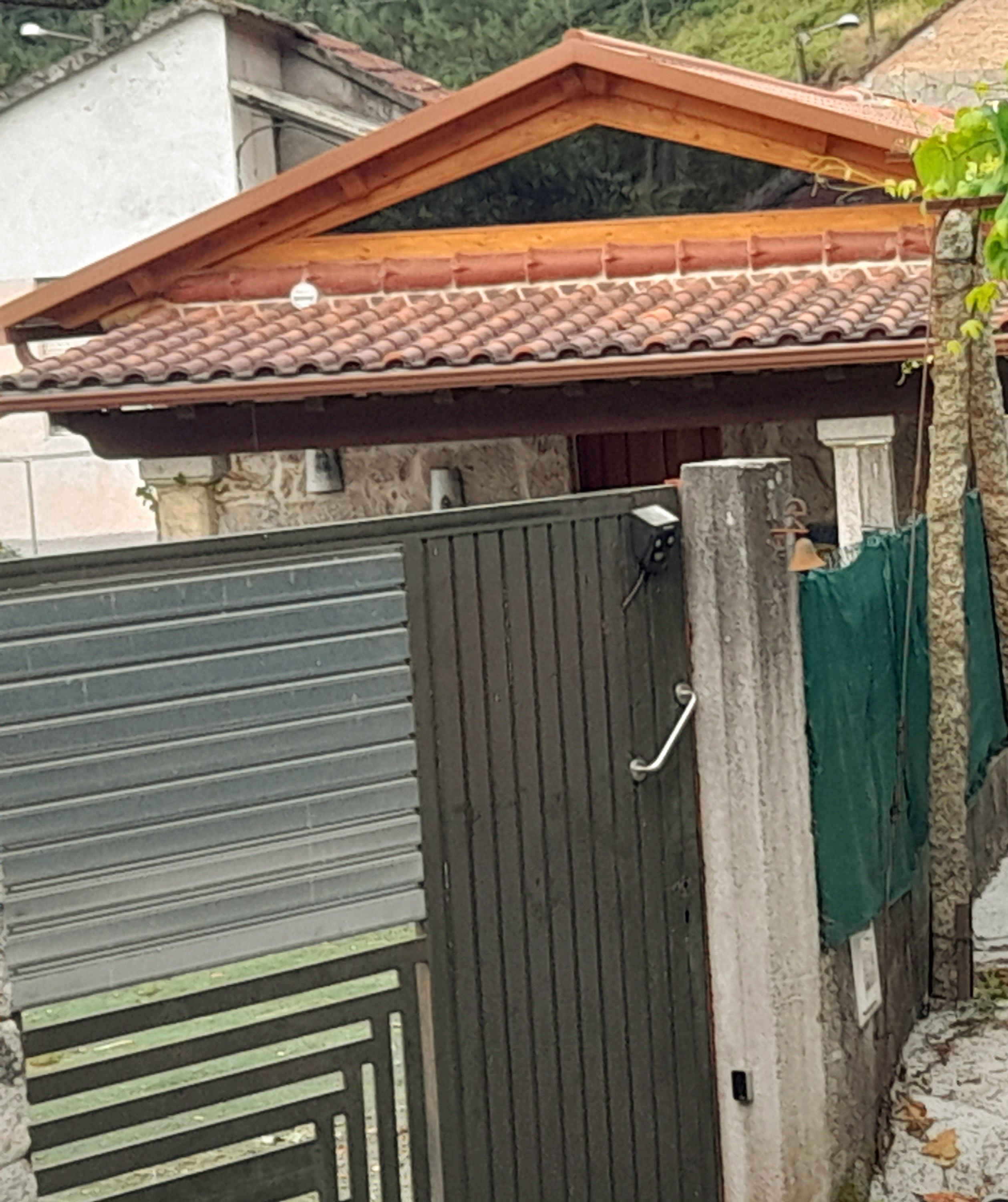 Una entrada con reja metálica y techo de tejas.