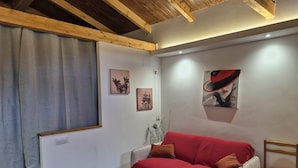 A cozy room with a wooden ceiling, a red sofa, a small wooden chair, and two wall-mounted paintings. - Rural House 'Paraje Do Cura' with Private Terrace and Wi-Fi (Arbo)