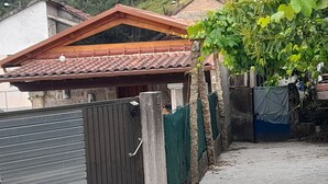 A gated area with a metal gate, a concrete pathway, and a building with a tiled roof. - Rural House 'Paraje Do Cura' with Private Terrace and Wi-Fi (Arbo)