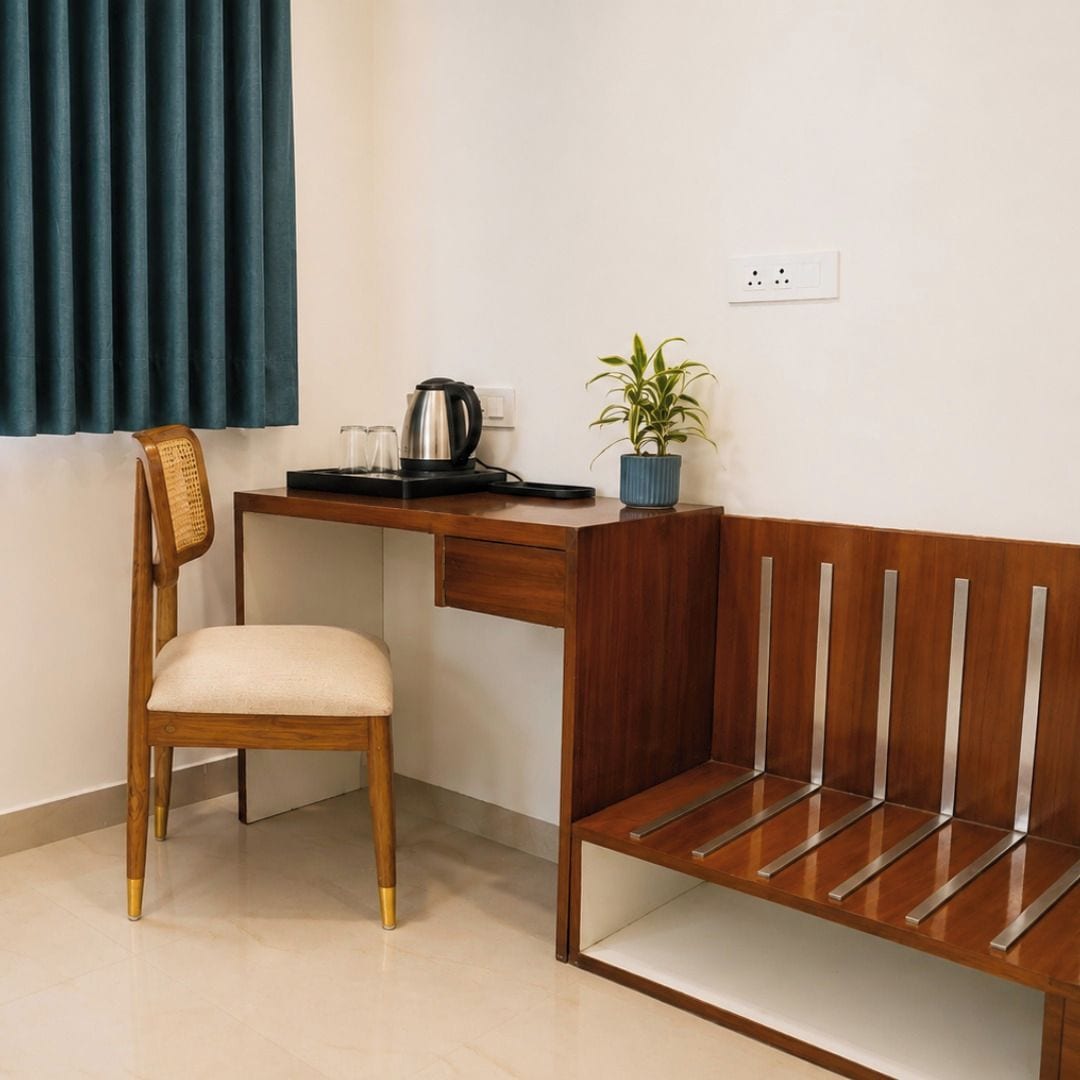 A room with a wooden desk, a chair, a bench, a potted plant, and a kettle.