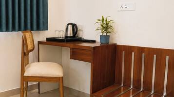 A room with a wooden desk, a chair, a bench, a potted plant, and a kettle.