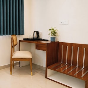 Une pièce comprenant un bureau en bois, une chaise, un banc, une plante en pot et une bouilloire.