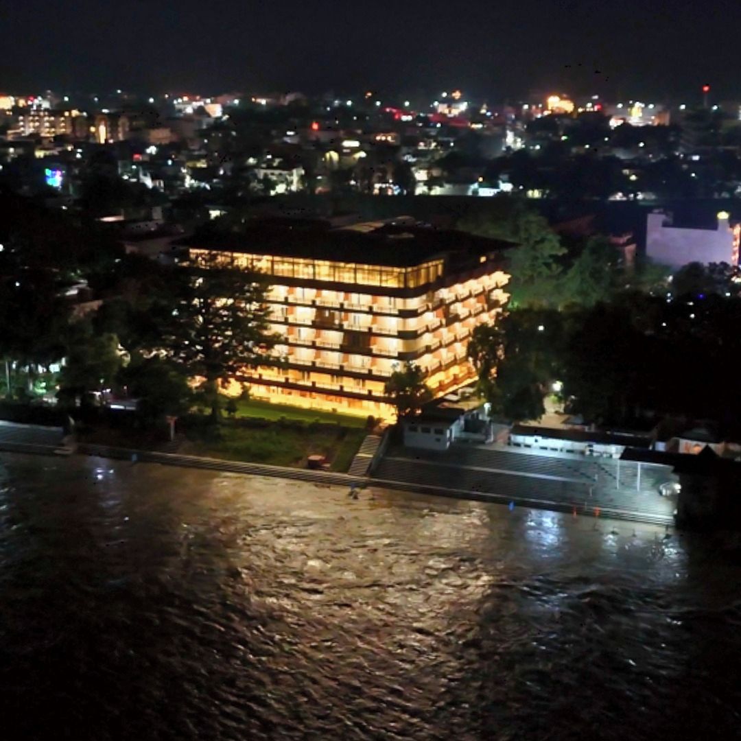 A multi-story building with illuminated windows, situated near a body of water.
