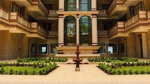 A multi-story building with a central courtyard, a fountain, and a symmetrical facade with balconies. - Kamdhenu Lok (Haridwar)