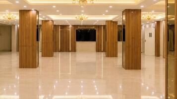 Un amplio vestíbulo de hotel con techo alto, candelabros y pilares de madera.