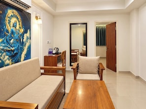 A modern living room with a sofa, a wooden coffee table, and a painting on the wall.