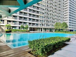 A modern apartment building with a swimming pool, balconies, and a landscaped garden area. - Royal Fame Residence (Mandaluyong)