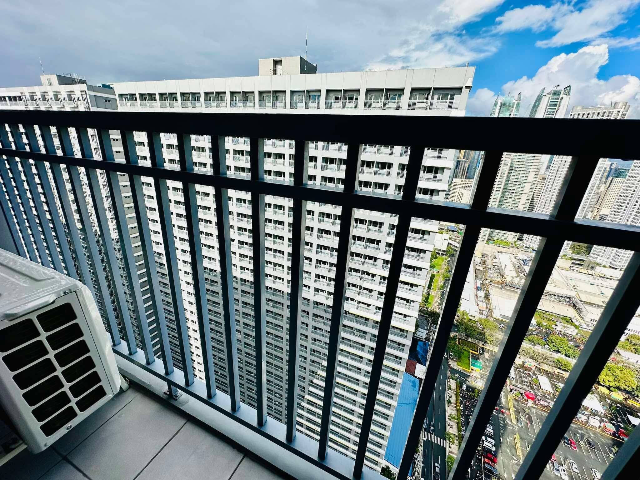 A high-rise building with a view of a cityscape through a balcony railing.