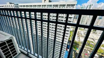 A high-rise building with a view of a cityscape through a balcony railing.