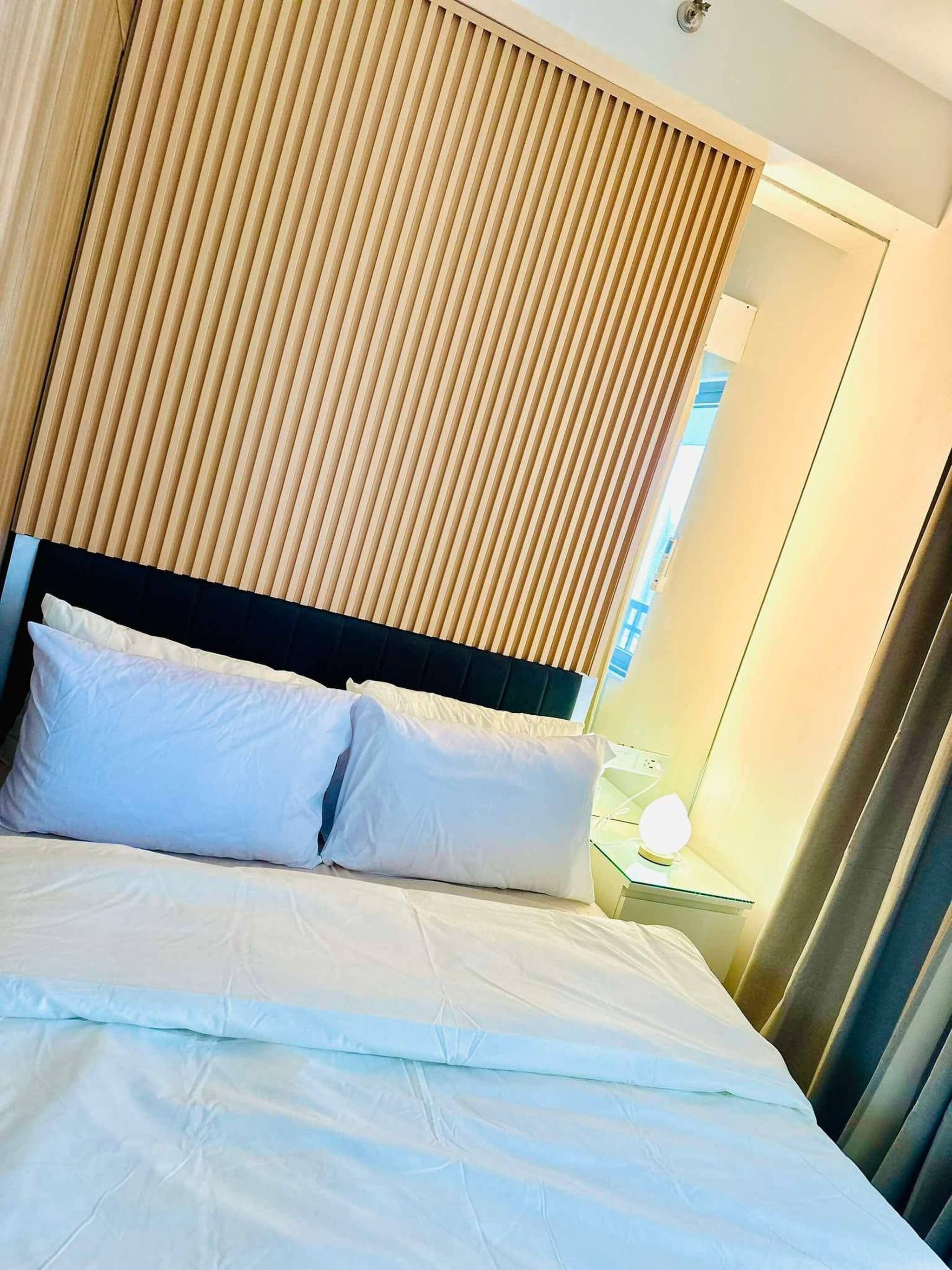 Una habitación de hotel con una cama, una mesita de noche y una ventana con cortinas.