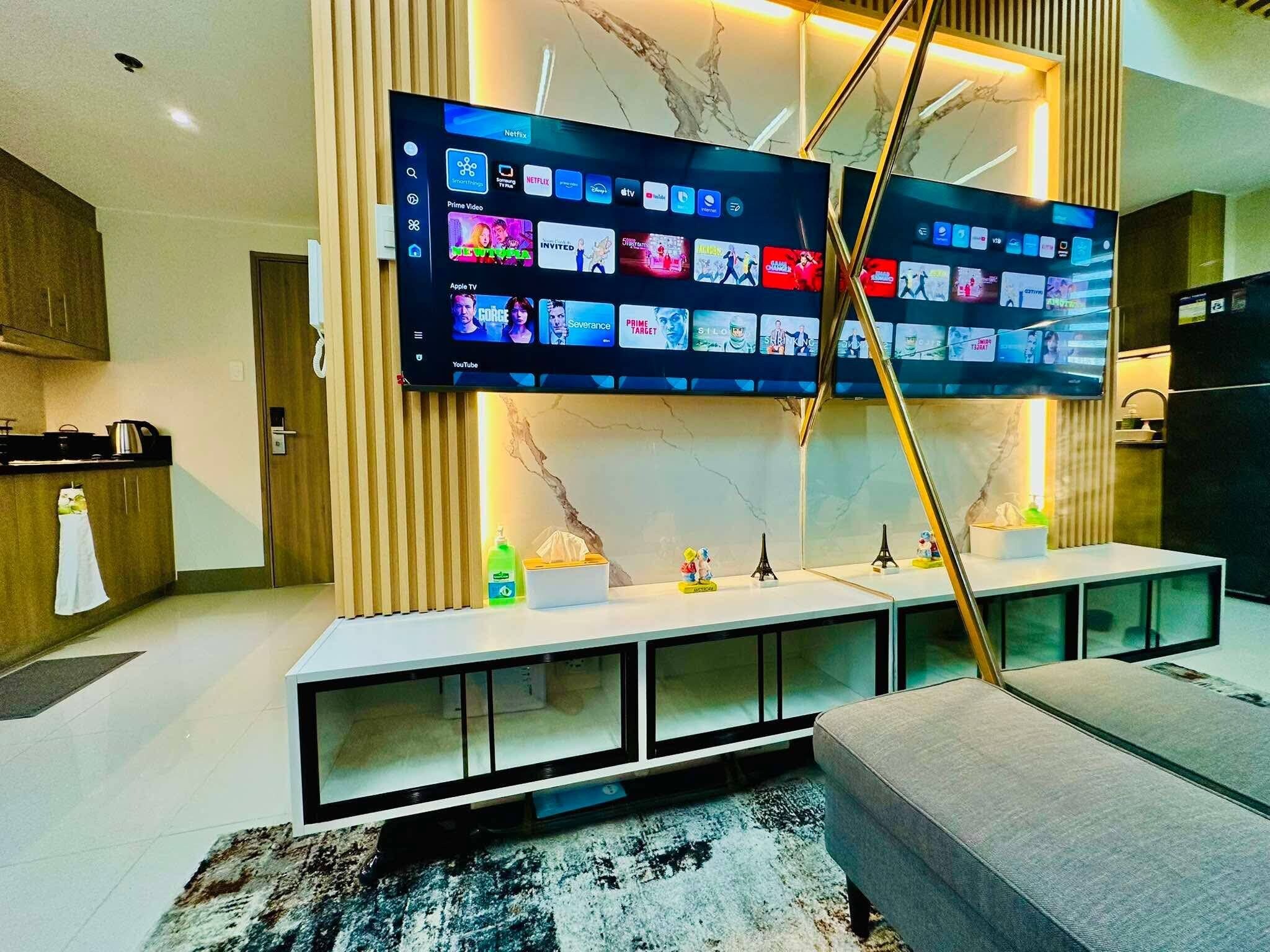 Un salon moderne doté d’un grand téléviseur à écran plat fixé au mur, qui permet d’accéder à différents services de diffusion en continu.