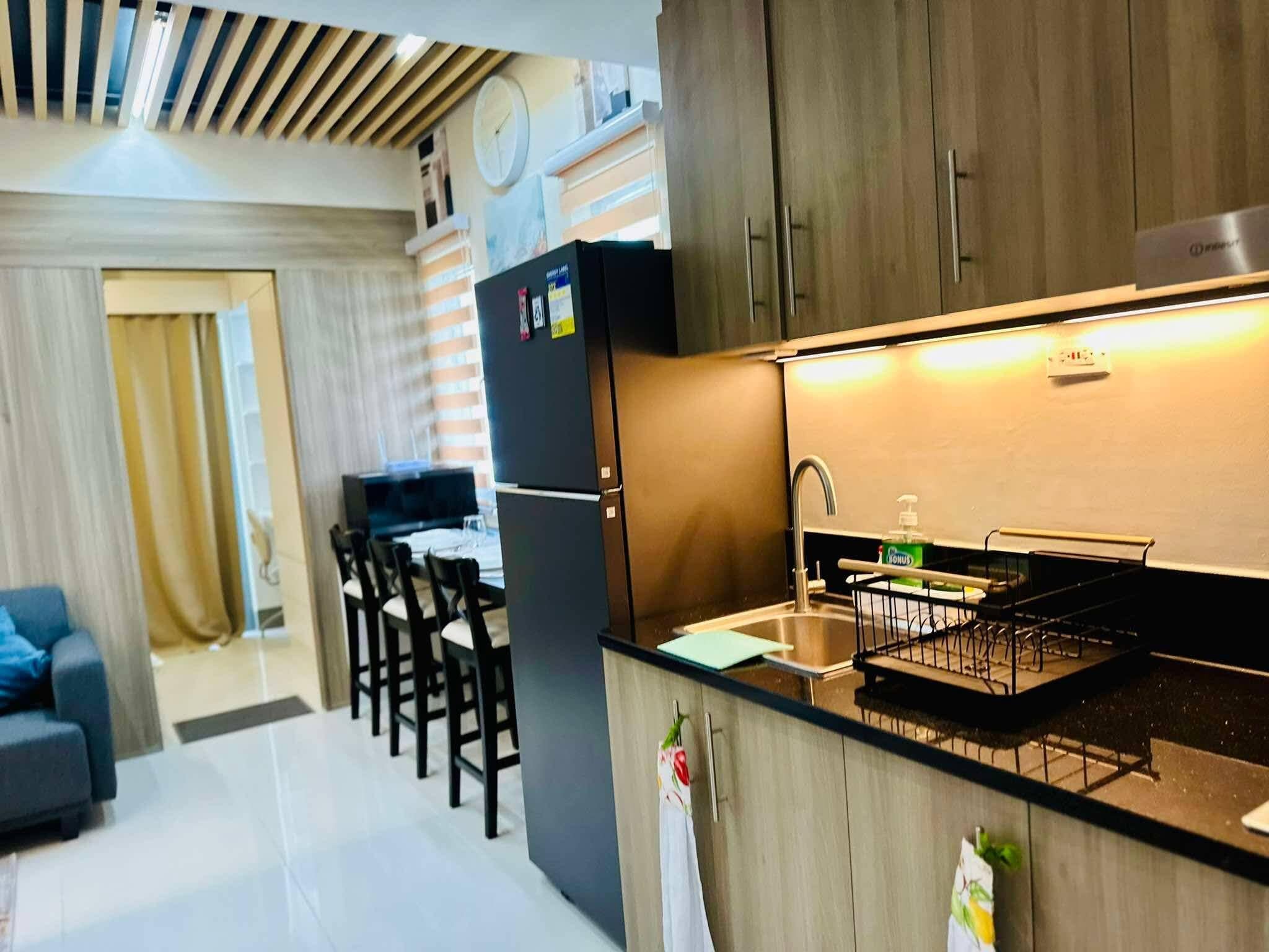 A compact kitchen with a built-in oven, a sink, and a dining area with chairs.