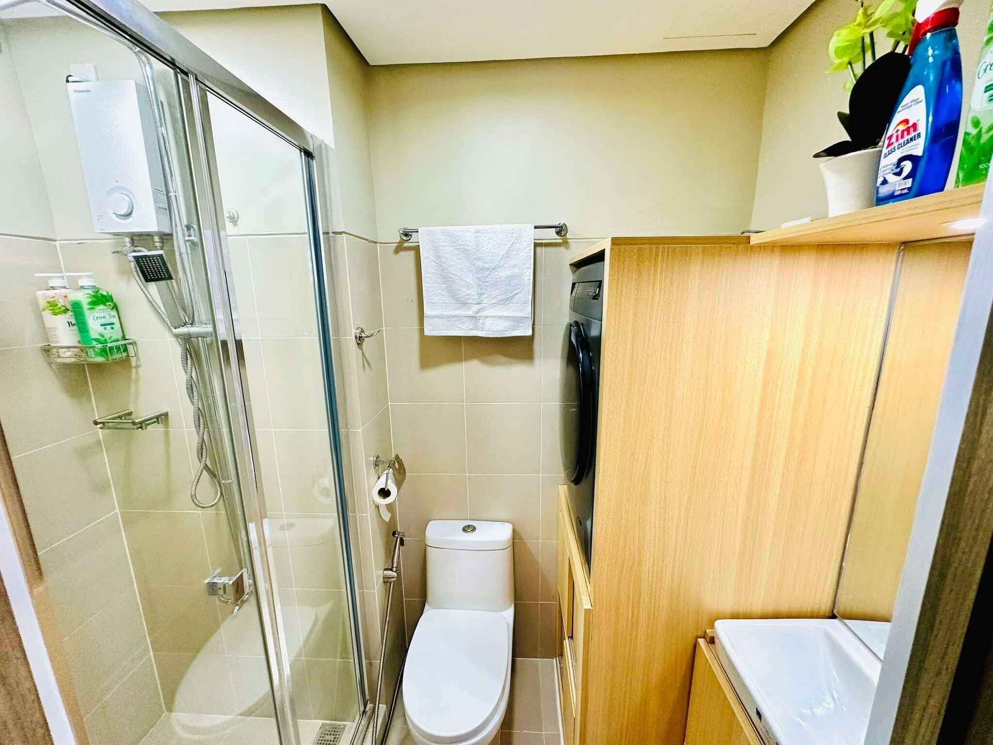 A compact bathroom with a glass shower enclosure, a toilet, and a sink.